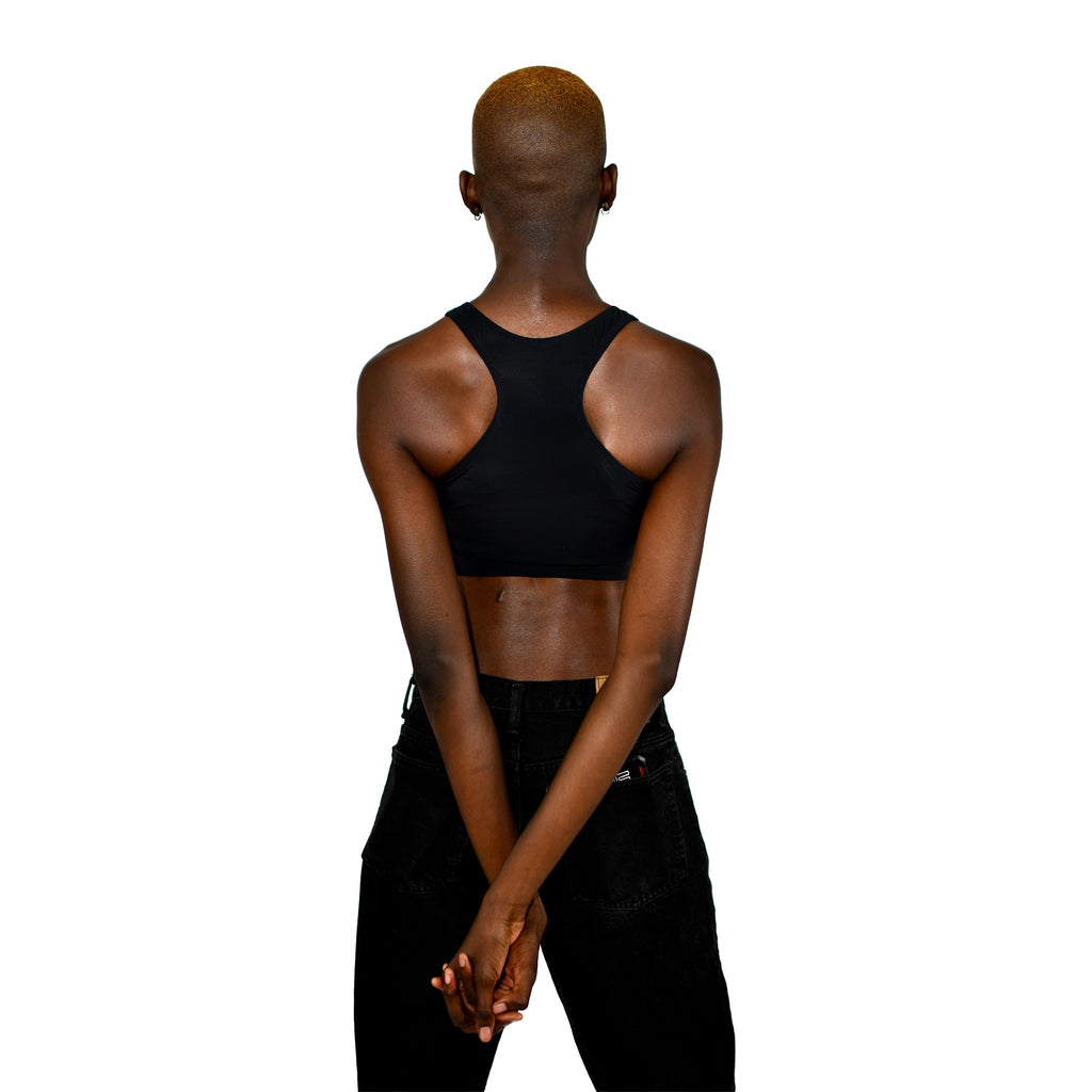 Model shows off a black racerback binder, back to the viewer with hands clasped behind the back.